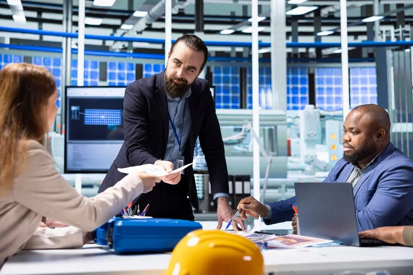 Менеджер фабрики передает папки с документами инвесторам, изучающим финансовую отчетность.